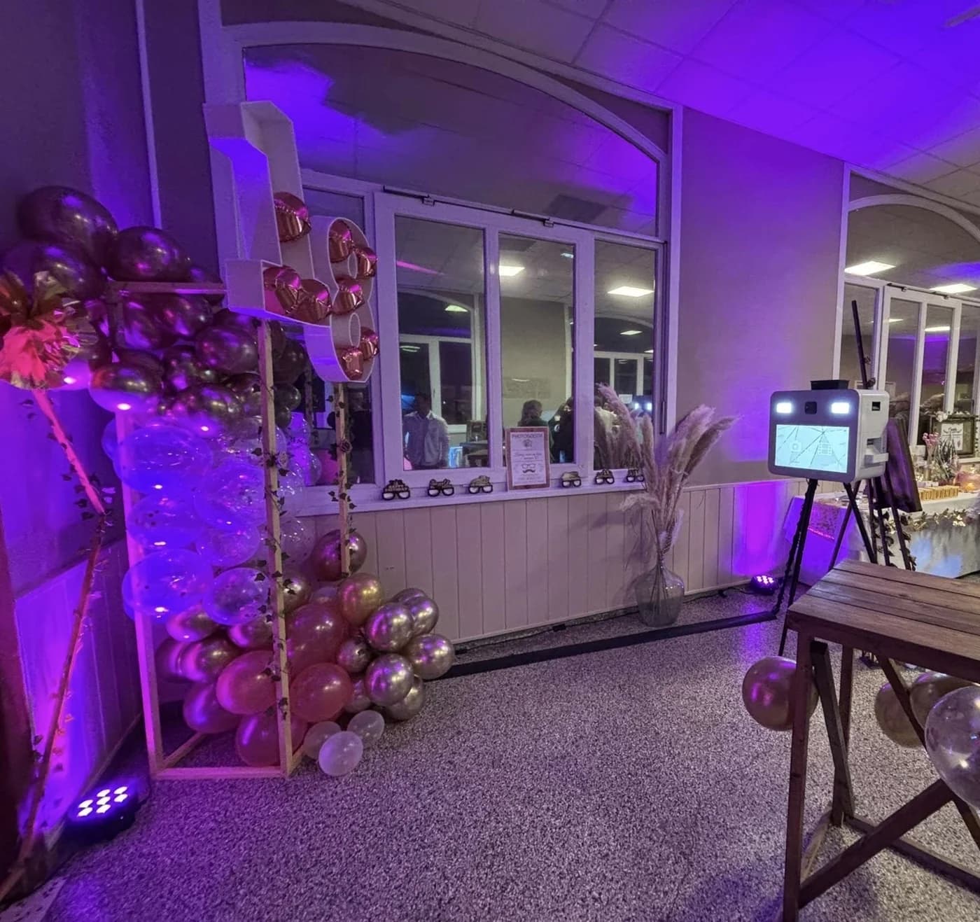 Le photobooth SELPHOTO dans une salle décorée de ballons, éclairée en violet